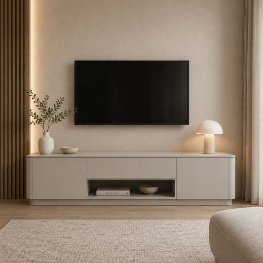A modern light gray media console in a minimalist living room setting, styled with a black flat-screen TV, a white vase with greenery, a small bowl, and a white table lamp.